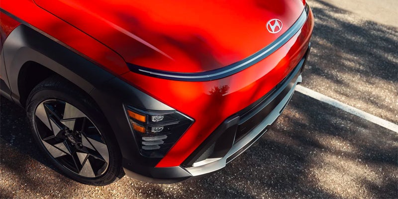 Front corner view of red Hyundai Kona in sunlight