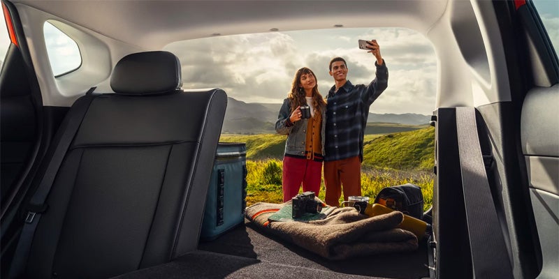 Hyundai Kona parked with couple taking selfie by mountain view
